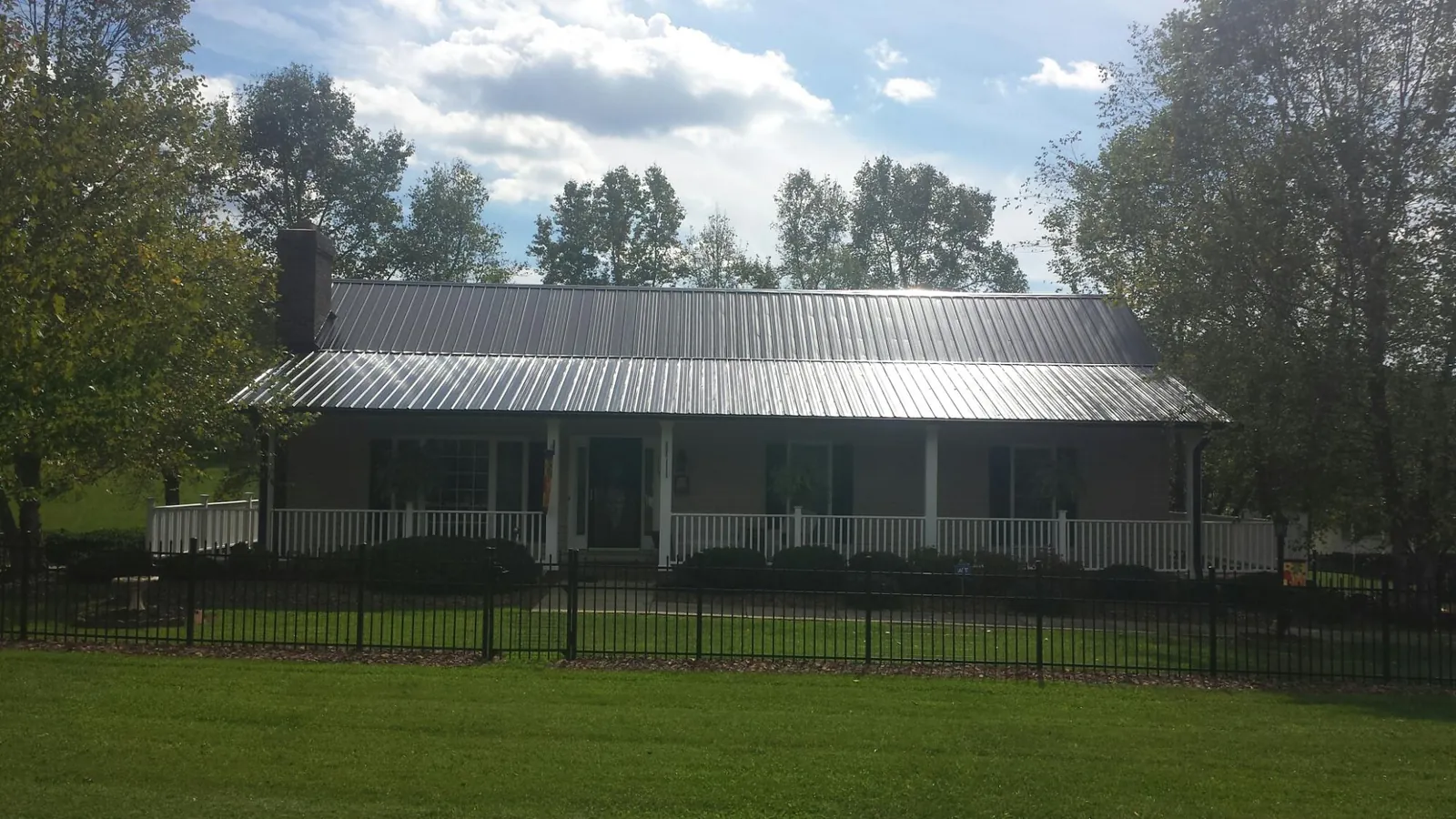 Gray metal roof on a brick ranch with a full width front porch — Gutter Guard Installation work by our crew in Keene